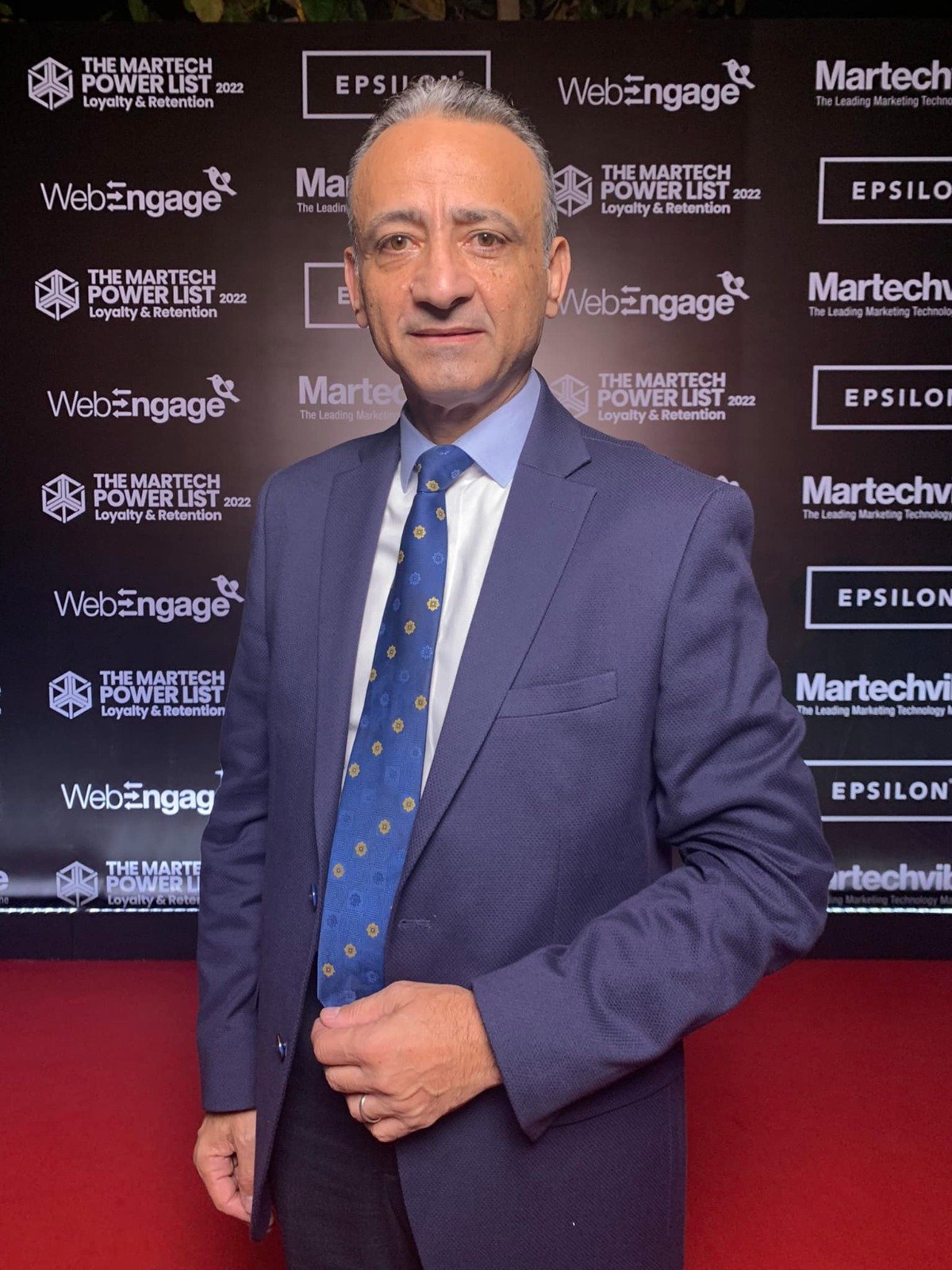 Man in suit at event backdrop.